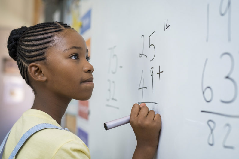 Girl learning about addition on a white board