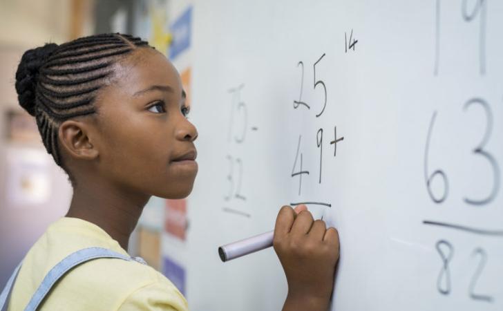 Girl learning about addition on a white board